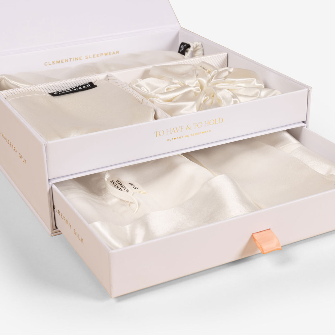Open white wedding gift box with compartments holding small floral accessories and cards, lid printed 'The Bride Box'