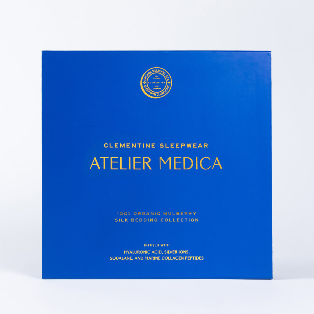 Blue box with gold text: Clementine Sleepwear Atelier Medica, 100% Organic Mulberry Silk Bedding Collection, infused with hyaluronic acid, silver ions, squalane, and marine collagen peptides. - #color_pearl-white