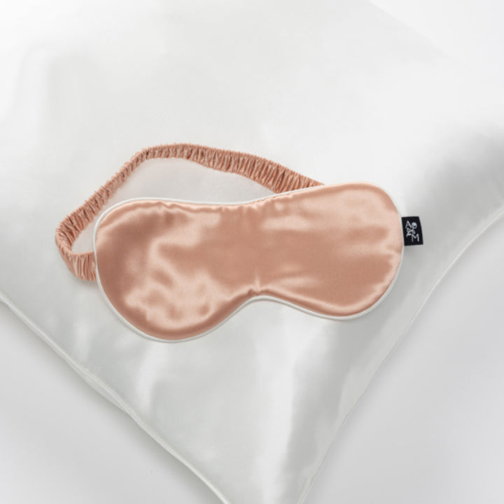 peach silk sleep mask with elastic strap on pearl-white silk pillow - #color_pearl-white
