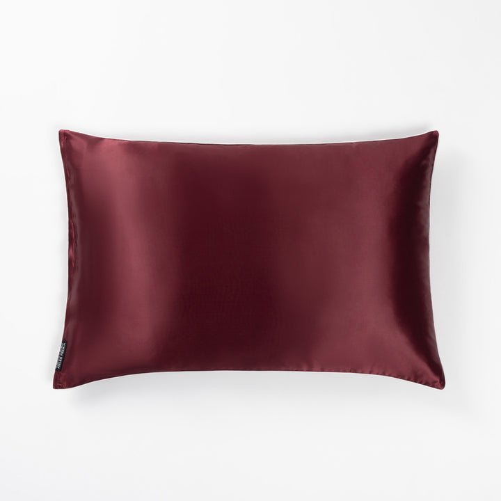 Plum-colored rectangular silk pillow with a small black tag on the side - #color_plum