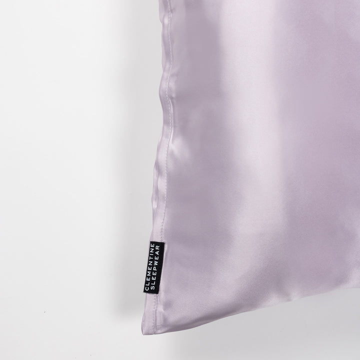 Lilac-haze silk pillow corner showing edge stitching and black tag reading 'CLEMENTINE SLEEPWEAR'. - quality stitching silk pillow#color_lilac-haze
