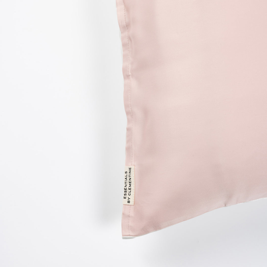 Pale ballet-pink pillowcase corner with vertical fabric tag reading ESSENTIALS BY CLEMENTINE - #color_ballet-pink