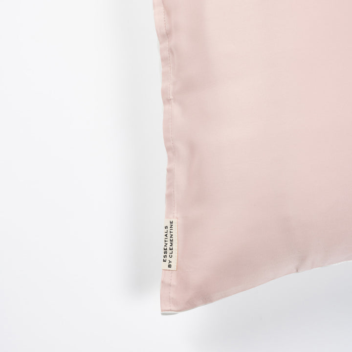 Pale ballet-pink pillowcase corner with vertical fabric tag reading ESSENTIALS BY CLEMENTINE - #color_ballet-pink