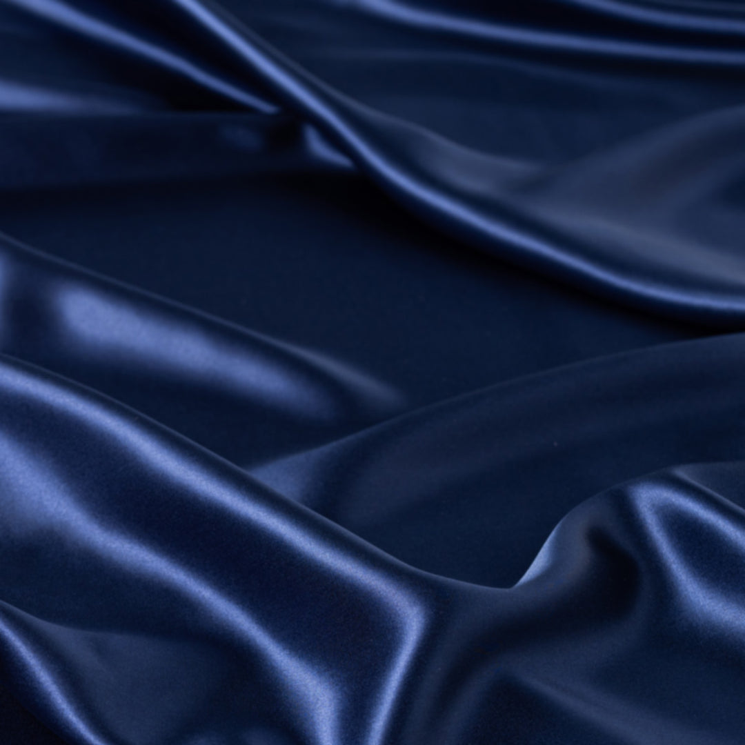 Deep navy organic silk fabric with glossy sheen and soft flowing folds, texture detail for duvet cover