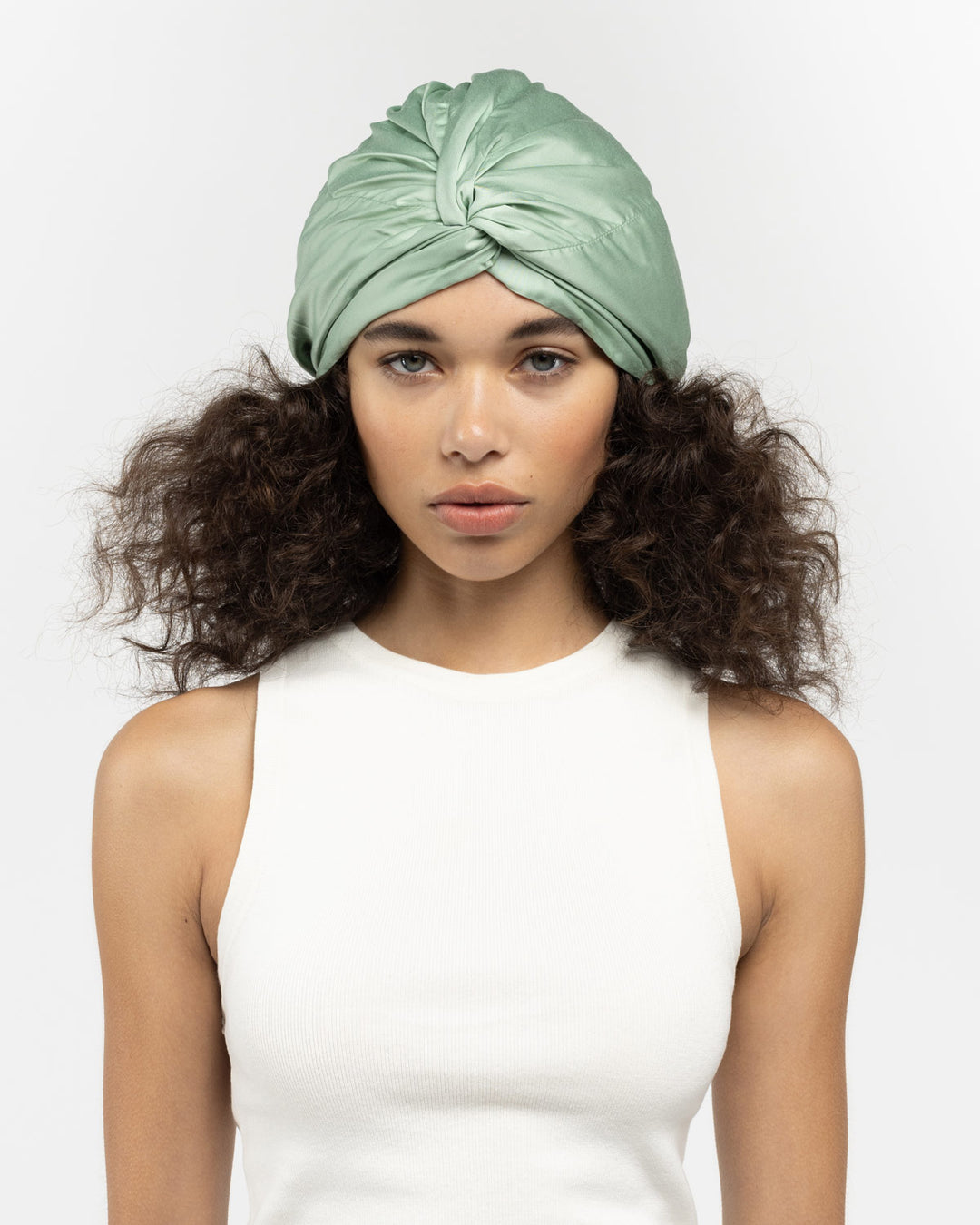 Model wearing sage-green twisted turban-style silk hair bonnet