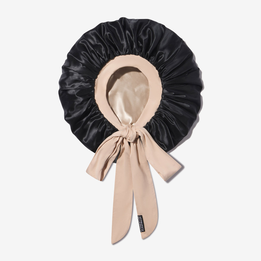 Black silk sleep bonnet with beige silk lining and long beige ties knotted at front