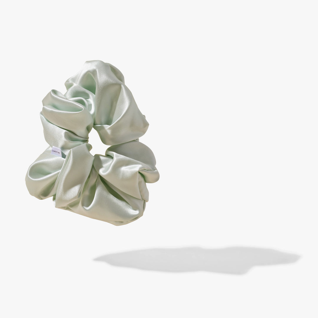 Mint organic silk scrunchie with satin sheen, floating above a soft shadow