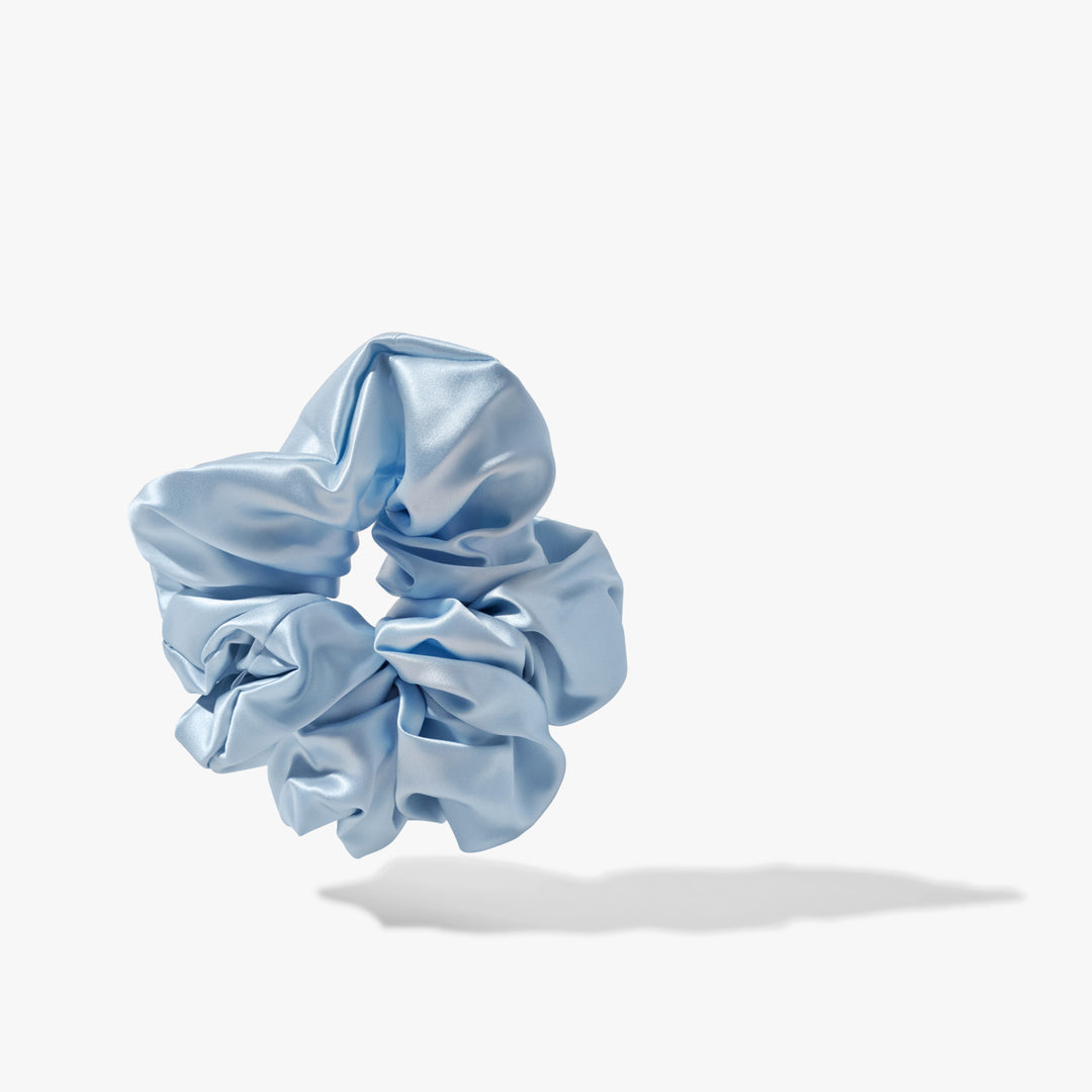 Pale sky-blue organic silk scrunchie with soft sheen and cast shadow