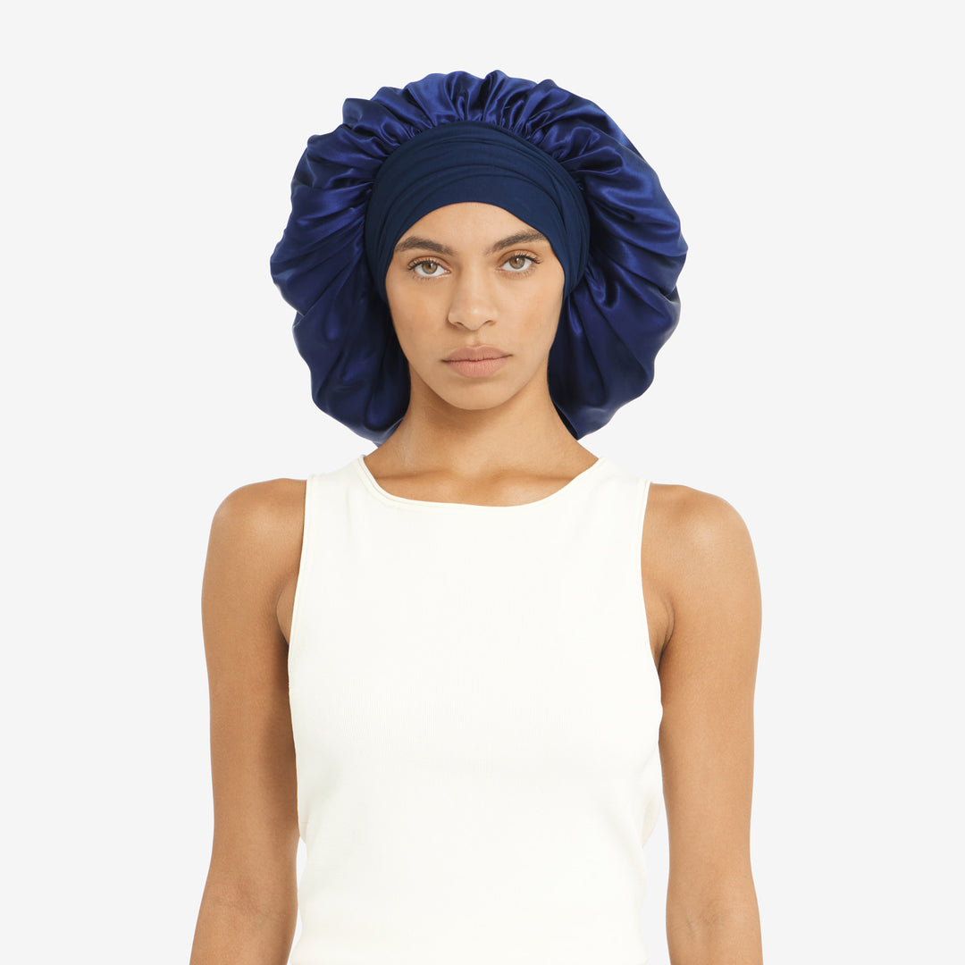 Front-facing woman wearing oversized navy silk bonnet with matching turban-style band