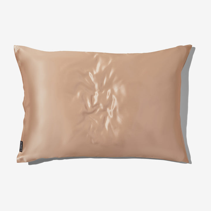 Champagne-gold organic silk pillowcase with brand tag reading SLIP, flat lay on neutral background#color_champagne-gold