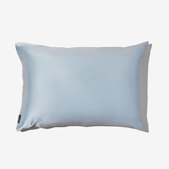 Sky-blue silk pillowcase on white background, rectangular pillow with small black brand tag at lower left. - luxury silk pillowcase blue#color_sky-blue