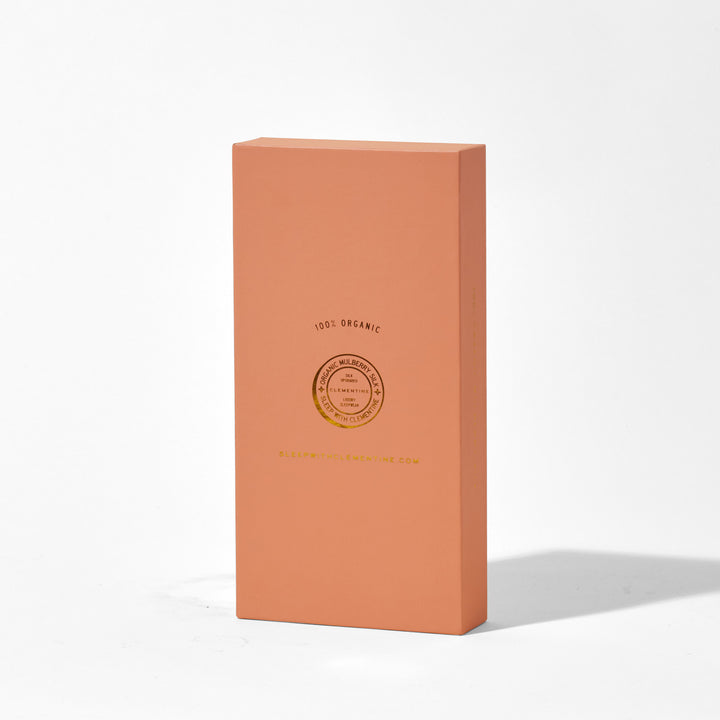 Tall champagne-gold pillowcase gift box with gold foil circular seal; stamped "100% ORGANIC" and "SLEEPWITHCLEMENTINE.COM". - luxury pillowcase packaging foil#color_champagne-gold