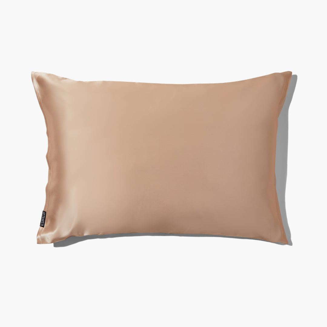 Champagne-gold silk pillowcase with subtle sheen and small black brand tag at lower left - luxury silk pillowcase gold#color_champagne-gold