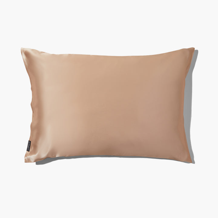 Champagne-gold silk pillowcase with subtle sheen and small black brand tag at lower left - luxury silk pillowcase gold#color_champagne-gold