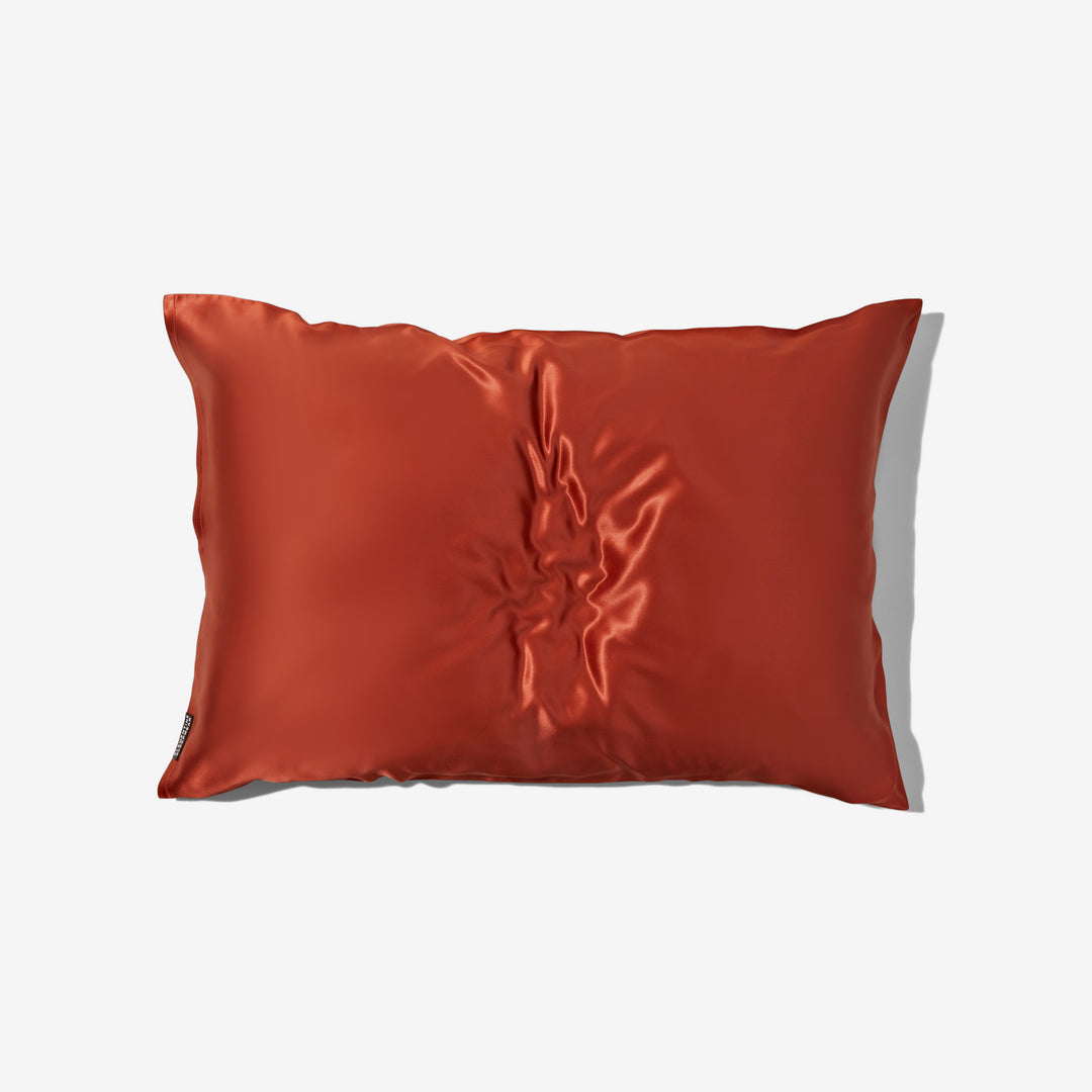 Top-down view of dusk maroon organic silk pillowcase with center wrinkles on white background. - organic silk pillowcase dusk maroon#color_dusk