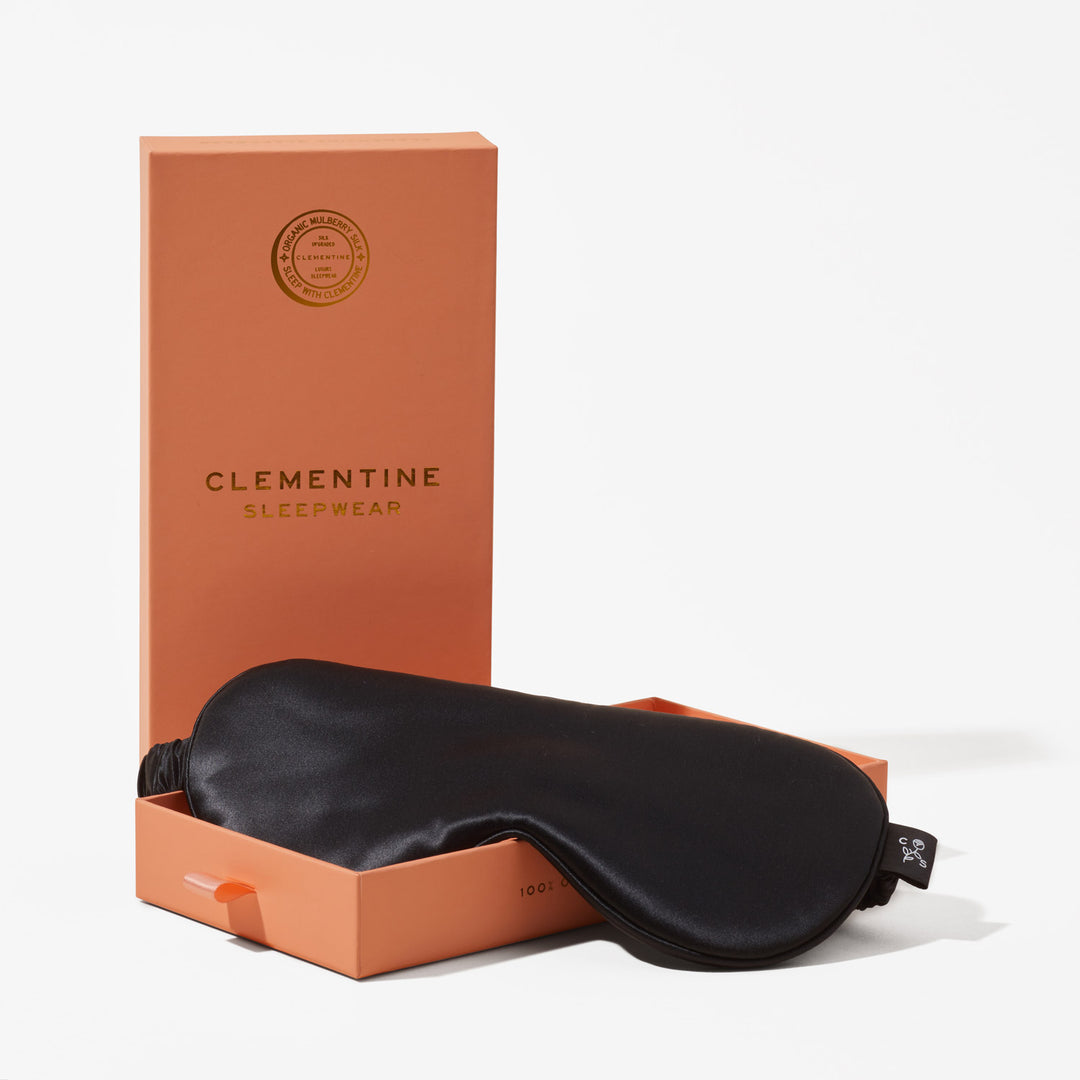 Black organic silk sleep mask resting on orange box labeled CLEMENTINE SLEEPWEAR