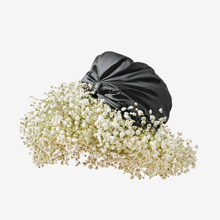 Black silk hair bonnet nestling on a mass of white baby's-breath flowers