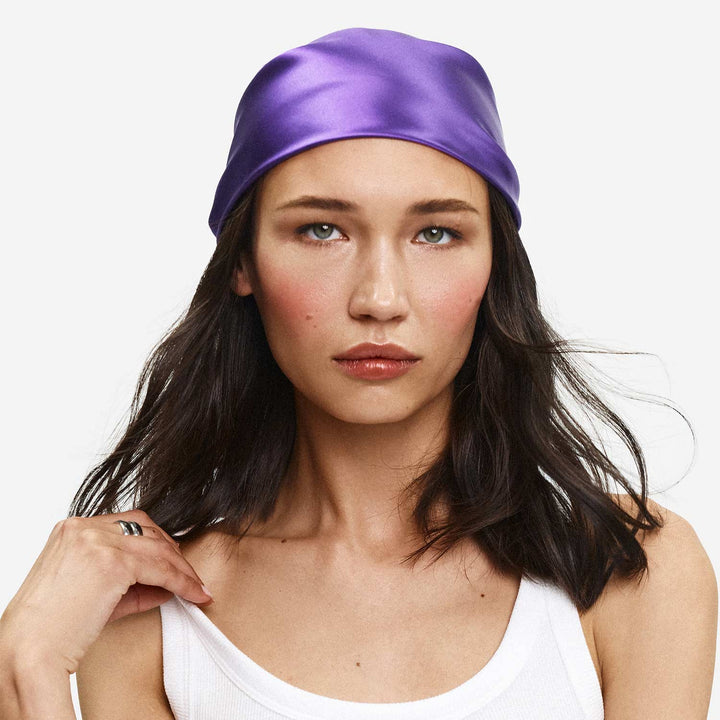 Woman wearing a purple satin headband on a white background. #color_ultraviolet
