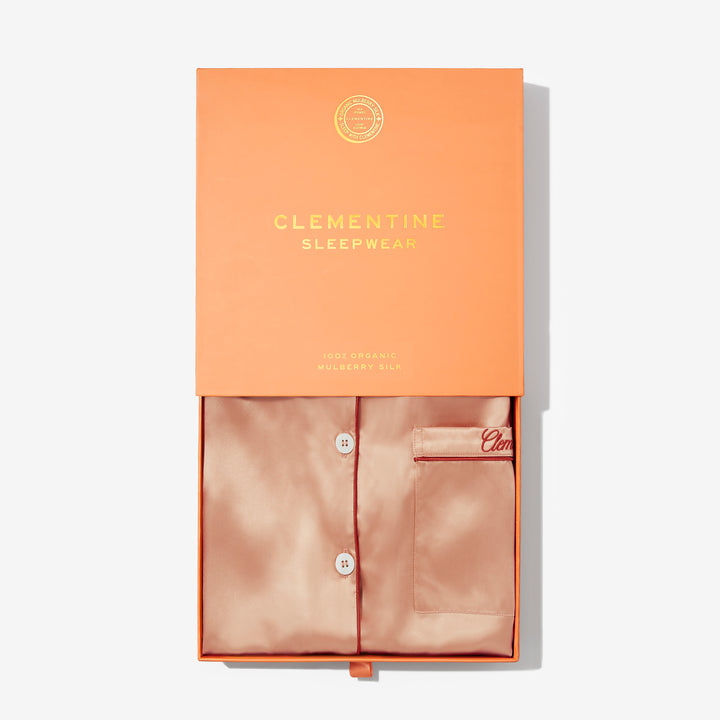 Silk pajama set in a Clementine Sleepwear box on a light gray background #color_clementine-peach-and-dusk