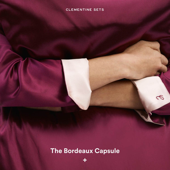 CLEMENTINE SETS — folded bordeaux satin pajama top with ivory cuffs; text reads 'The Bordeaux Capsule'