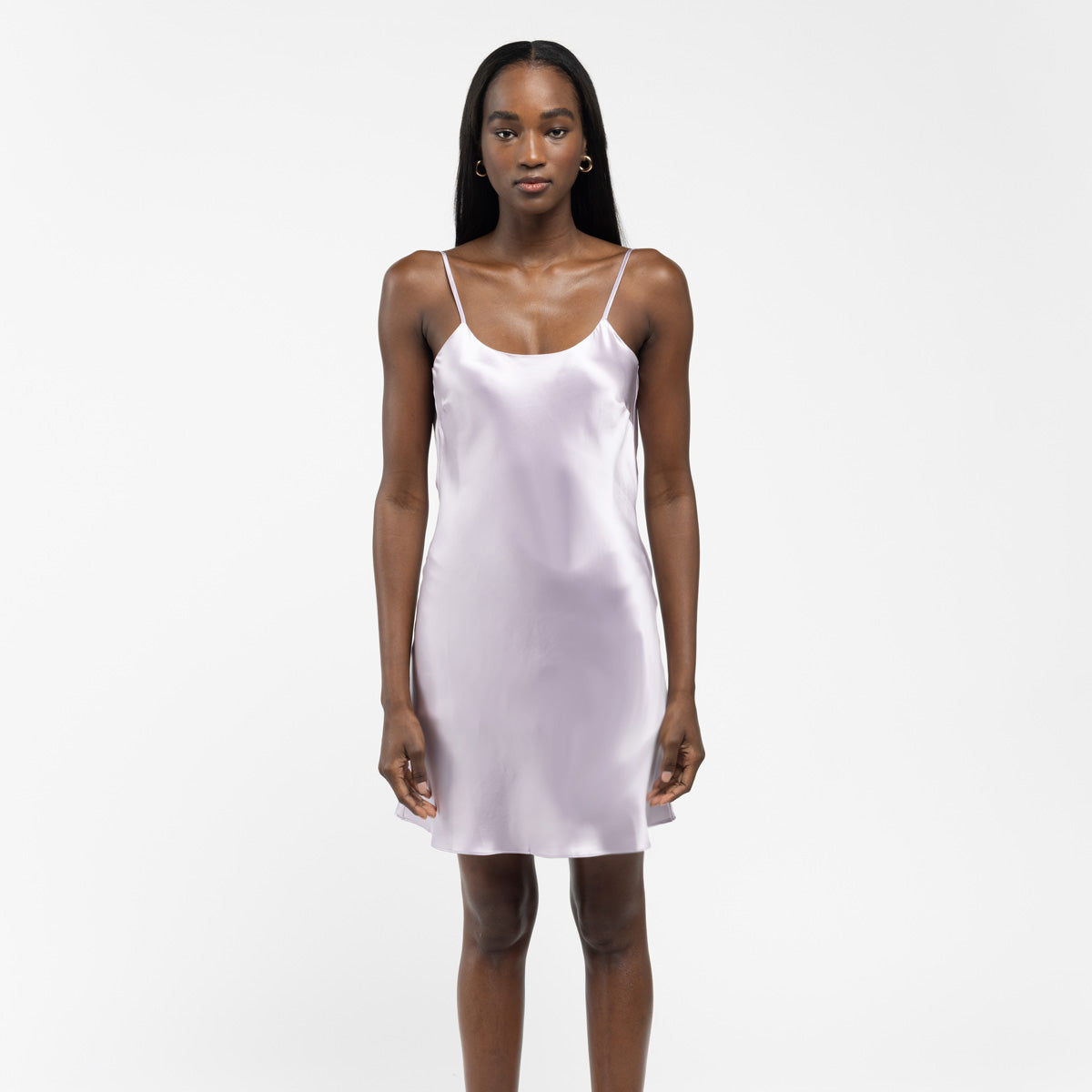 Woman wearing a lilac silk slip dress with thin straps, standing against a white background. - #color_lilac-haze