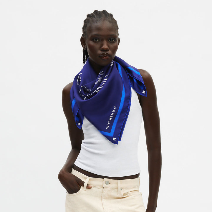 Model wearing deep blue silk scarf tied at the neck with triangular drape; vertical text 'CREWELINE' visible.
