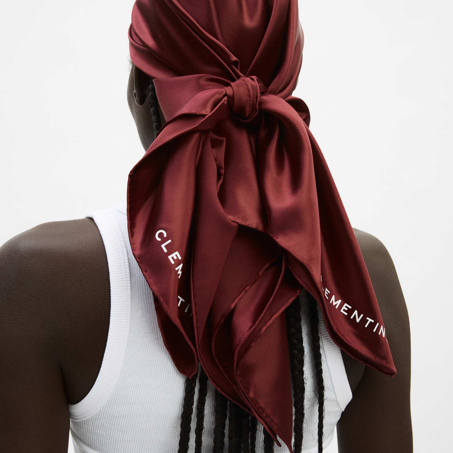 Burgundy silk scarf tied at back of head over braids, white tank visible; scarf shows text CLEM and EMENTIN.