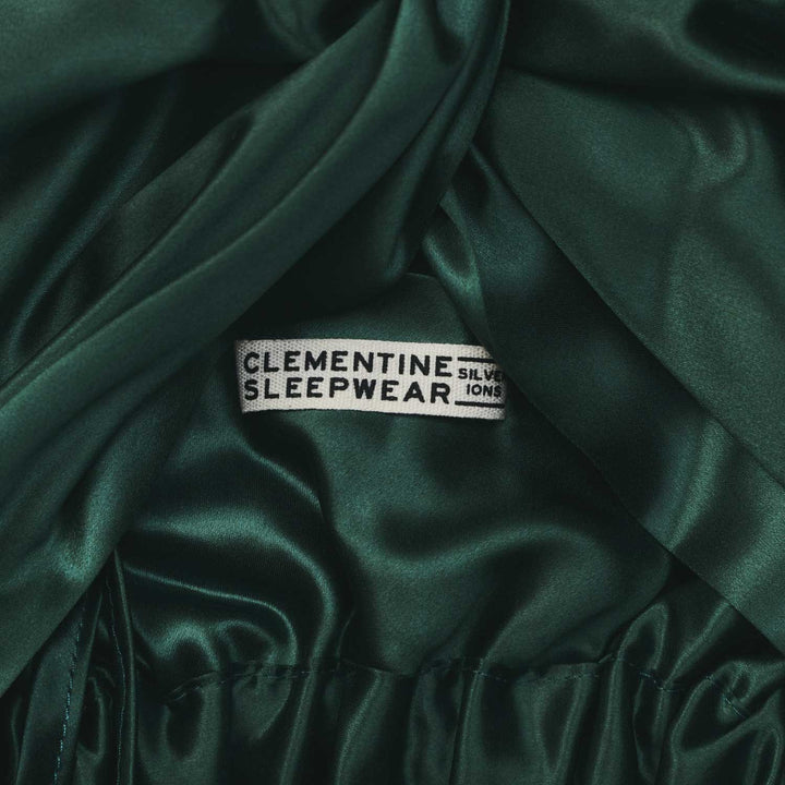 Dark green silk fabric with a label reading 'Clementine Sleepwear' on a dark background. #color_forest-green