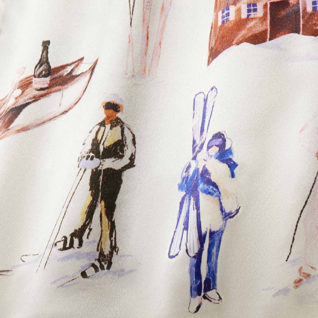 Two illustrated skiers on fabric: one with poles, one carrying skis; chalet and wine bottle motifs in the background.