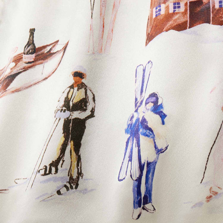 Two illustrated skiers on fabric: one with poles, one carrying skis; chalet and wine bottle motifs in the background.