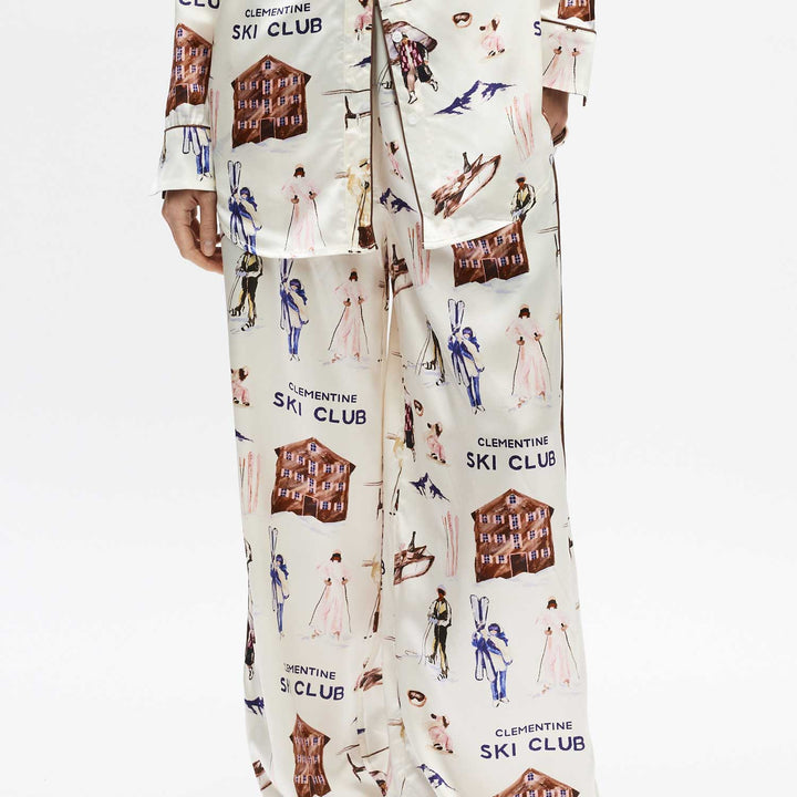 Silk pajama pants with vintage ski-club illustrations and repeated text 'CLEMENTINE SKI CLUB'.