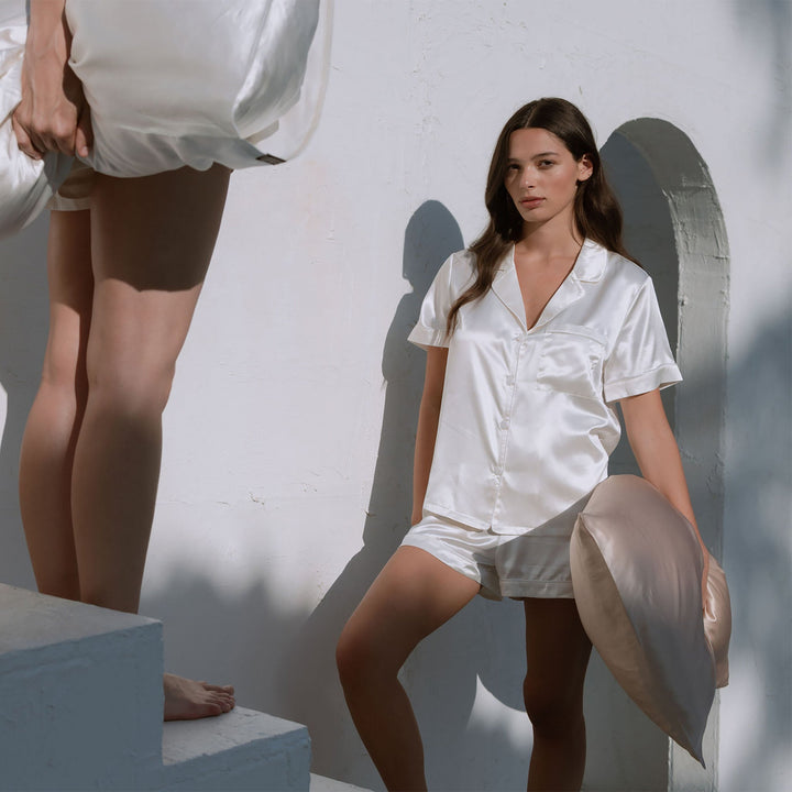 Organic white silk pajamas on steps outdoors#color_pearl-white