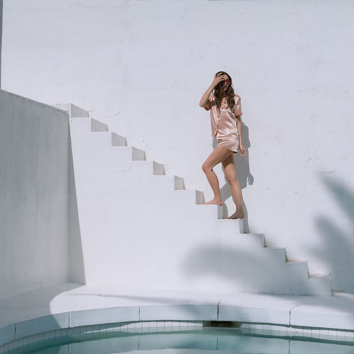 Walking up steps outdoors in silk pajamas#color_clementine-peach-and-dusk