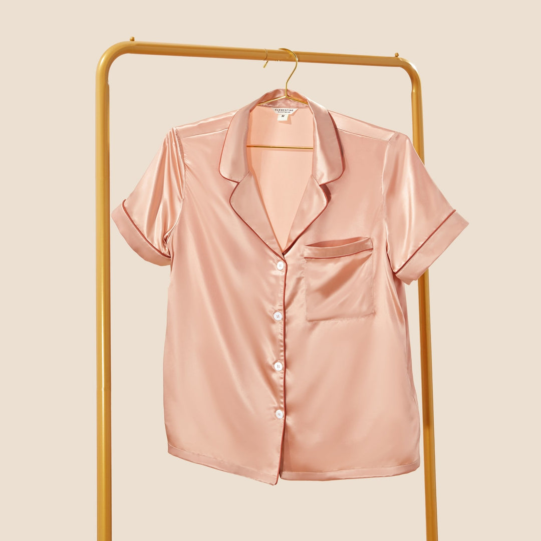 organic peach silk pajamas on rack#color_clementine-peach-and-dusk